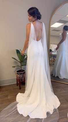 a woman in a wedding dress looking at herself in the mirror with her back to the camera