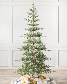 a small christmas tree sitting on top of a white plate with presents under the tree