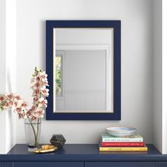 a blue dresser with flowers and a mirror on the wall in a white walled room