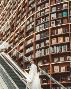 a woman standing on an escalator in front of bookshelves