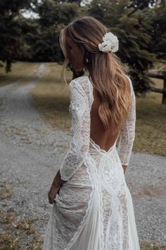 the back of a woman's wedding dress with long sleeves and an open back