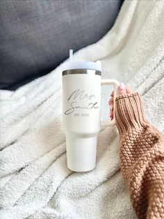 a person holding a coffee cup on top of a blanket