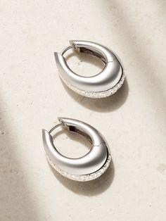 Designer Ananya Malhotra’s Indian heritage and spiritual upbringing inspire ANANYA's striking pieces. Cast from 18-karat white gold, these 'Chakra Icon' hoop earrings are defined by a sleek, chunky profile traced by a channel of round-cut diamonds. Pair yours with the matching bracelet in our edit. Silver Classic Huggie Earrings With Halo Design, Ananya Bracelet, Timeless Silver Drop Hoop Earrings, Luxury Small Hoop Earrings Hallmarked, White Gold Teardrop Hoop Earrings With Polished Finish, Modern Silver Jewelry With Halo Design, Luxury Silver Diamond Earrings With Pave Setting, Silver Fusion Jewelry With Diamond Accents, Luxury Oval Earrings With Shiny Finish