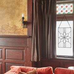 a living room with red couches and stained glass windows in the corner, along with wooden paneling