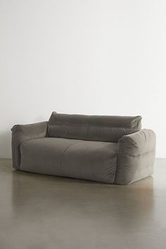 a gray couch sitting on top of a floor next to a white wall in an empty room