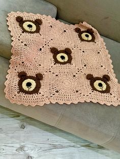 a crocheted blanket with teddy bears on it is sitting on a couch next to a pillow