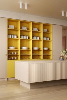 an empty room with yellow shelves and white dishes