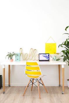 a yellow chair sitting in front of a white table with a laptop on top of it