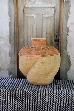 a large vase sitting on top of a black and white checkered bench next to a wooden door