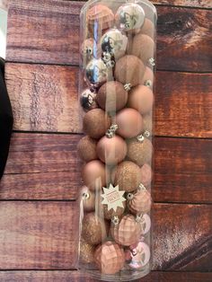 a glass container filled with assorted ornaments on top of a wooden table next to a wall