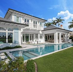 a large white house with a pool in the front yard and palm trees around it