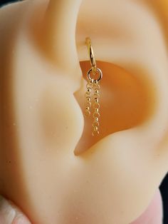 a close up of a person's ear with a gold chain attached to it