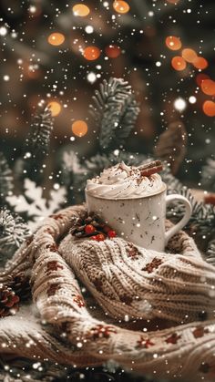 a cup of hot chocolate with whipped cream and cinnamon sticks on a blanket in front of a christmas tree