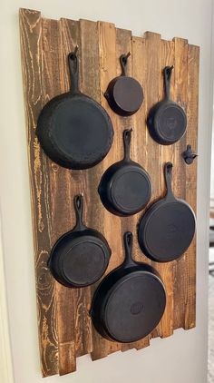 an assortment of cast iron pans mounted to a wooden wall hanging on a door