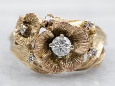 a close up view of a gold ring with flowers and diamonds on the side,