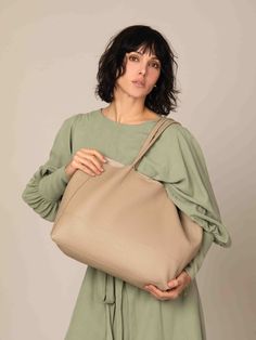 a woman is holding a large beige bag