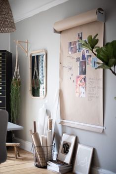 a desk with various items on it in front of a large poster and hanging plant