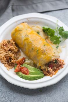 an enchilada on a plate with rice, avocado and cilantro