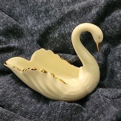 a white swan shaped object sitting on top of a gray blanket