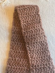 a brown crocheted tie laying on top of a white blanket