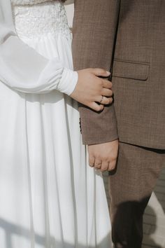 a man and woman standing next to each other holding hands