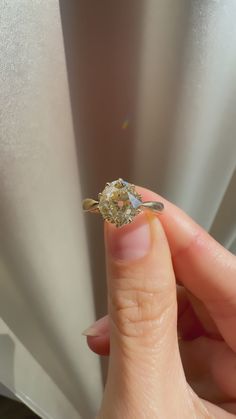 a woman's hand holding an engagement ring with a yellow diamond on the side