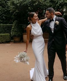 a man and woman in formal wear standing next to each other on a dirt ground