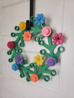 a wreath made out of plastic flowers and scissors hanging on the front door to decorate it