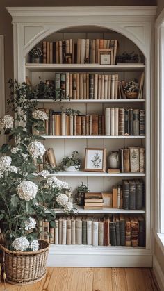 a bookshelf filled with lots of books next to a basket full of flowers