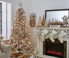 a living room decorated for christmas with a tree and stockings on the fireplace mantel