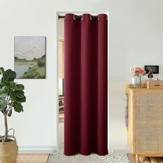 a living room with a red curtain in front of a white wall and a potted plant