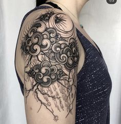 a woman's arm with clouds and sun tattoo on the back of her shoulder