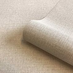 a close up view of the fabric on a beige couch with a white wall in the background