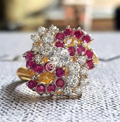 a close up of a ring with diamonds and rubishes on a white surface