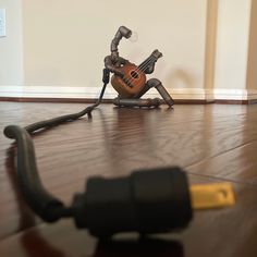 a small toy sitting on top of a wooden floor next to a microphone and violin