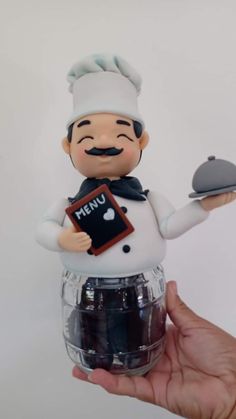 a hand holding a plastic chef figurine with an empty plate in it's left hand