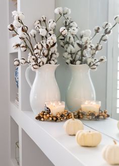 two white vases filled with flowers and candles