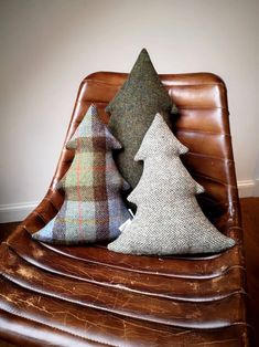 three christmas trees sitting on top of a brown chair