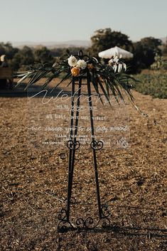 a sign with flowers on it in the middle of an open field and dirt ground