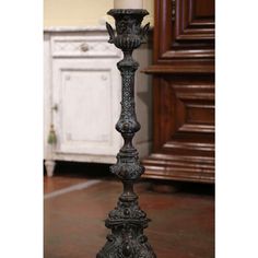 a tall metal candle holder sitting on top of a floor