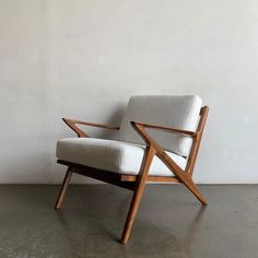 a white chair sitting on top of a cement floor next to a wooden framed wall