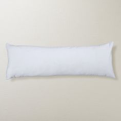 a white pillow sitting on top of a bed next to a beige wall and floor