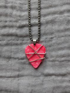 a pink heart shaped pendant on a black chain