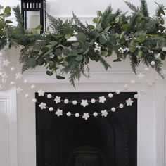 a fireplace decorated for christmas with greenery and lights