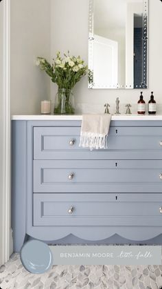 a bathroom vanity with blue drawers and white counter tops, along with a mirror above it