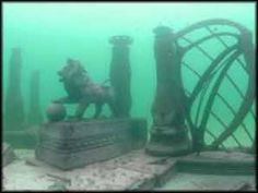 an underwater photo of a horse statue in the water next to some pillars and poles