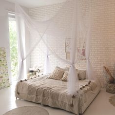 a bedroom with white brick walls and canopy bed, rugs on the floor in front of it