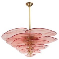 a pink flower shaped chandelier hanging from a gold ceiling fixture with red petals