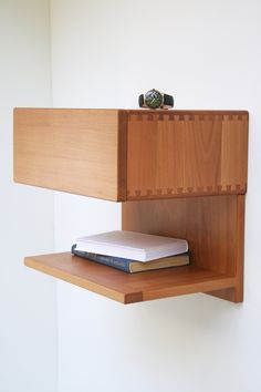 a bookshelf with a book on top of it next to a white wall