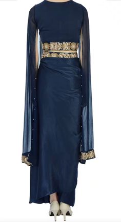 Saree is pre-stitched Saree is pre-pleated Saree is pre-made Stunning navy blue saree that has a pleated maxi skirt with floral motif work paired with cape-style cropped blouse. This set comes with sequin embellished drape! The fabric is modal satin and georgette. Festive Georgette Dupatta With Draped Sleeves, Designer Saree Dress With Draped Sleeves, Georgette Dress With Cape Sleeves For Navratri, Festive Floor-length Lehenga With Draped Sleeves, Silk Floor-length Sets With Draped Sleeves, Floor-length Lehenga With Draped Sleeves For Reception, Traditional Dupatta With Draped Sleeves For Reception, Festive Floor-length Dupatta With Draped Sleeves, Festive Embellished Lehenga With Cape Sleeves